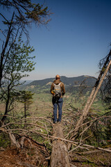 Adventurous Hiker Exploring Naturpark Ammergauer Alpen: Lone Figure Standing On Rocky Outcrop Overlooking Majestic Mountain Ridges And Lush Green Valley Under A Clear Blue Sky In Scenic Bavaria