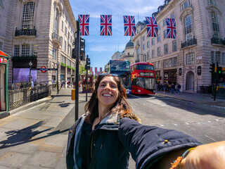 Tourist taking selfie in london with british flags and red bus
