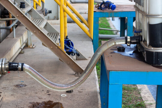 chemical caustic dispensed from IBC tank by hose connection, showing potential leak at valve. Industrial transfer process. hose, spill, leak, industrial, container.