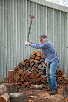 Man splitting logs of wood for fire in winter