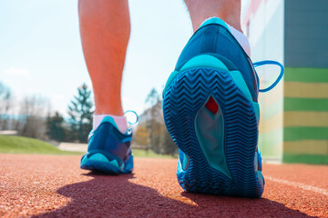 Close-up of male runner’s feet in athletic sneakers, captured in ready-to-run position. The athlete is preparing jog on outdoor surface, determination, active lifestyle. Fitness, sports motivation