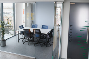 Modern office meeting room with glass walls and kitchen access