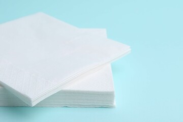 Stack of disposable paper handkerchiefs on light blue background, closeup
