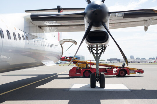 Luggage being loaded onto a plane with a propeller in foreground