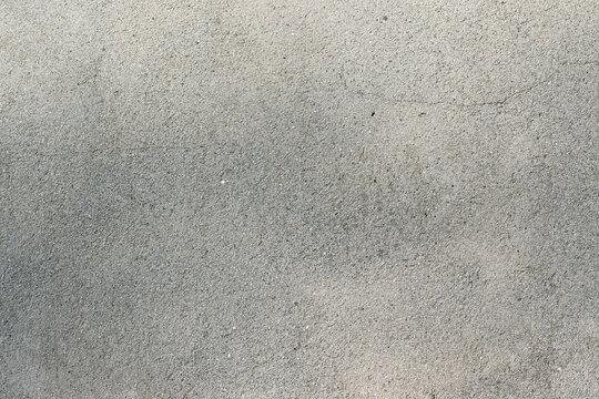 Un mur en ciment photographi&eacute; en plein cadre, r&eacute;v&eacute;lant sa texture brute, grise et industrielle, avec ses imperfections naturelles.
