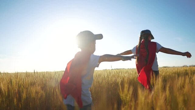 A group of kids playing a video game of superheroe together. Child hero fun concept. Superhero running through the wheat with children. A group of kids playing a sunset game of running together.