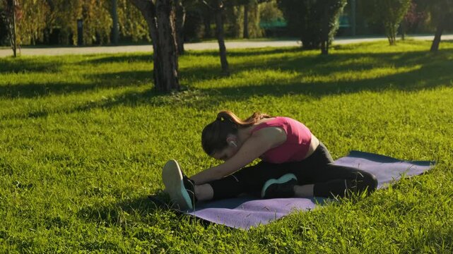 Young beautiful athletic girl in black leggings and red top doing morning exercises in city parken street. Fitness Stretching Warming-Up. Recreation Training Sportswear Warm-Up. Fitness Sport Workout