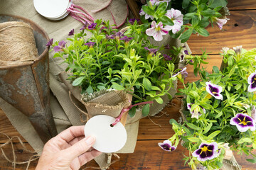 Hand holding the blank gift tag on a flower gift. Creating presents for attendees of a special event or garden party.