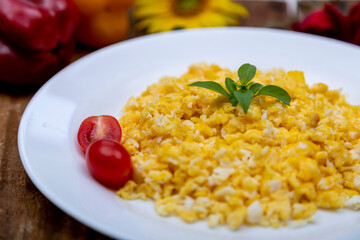 fresh scrambled eggs on white plate on breakfast table