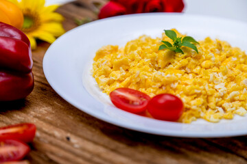 fresh scrambled eggs on white plate on breakfast table