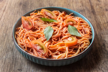spaghetti bolognese in a plate with sliced ​​tomatoes and basil leaves on wooden table