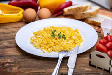 fresh scrambled eggs on white plate on breakfast table