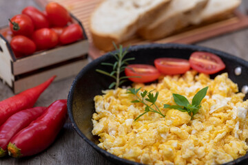 Scrambled eggs in an iron pan on the rustic wooden table