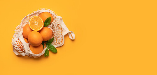 Ripe juicy oranges in cotton string bag on yellow background top view flat lay. Eco-friendly thread bag for shopping, buying food, fruits, vegetables. Zero waste, plastic free concept 