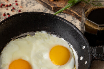 Fried eggs in the iron pan and cup of coffee for breakfast