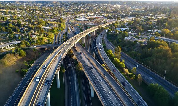 Expansive Freeway Interchange Under Clear Sky with Dense Green Trees at Sunset for Adobe Stock Photo