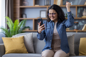 A woman celebrates good news she received on her phone, with an enthusiastic reaction.