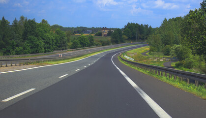Winding highway path surrounded by lush greenery in a sunny landscape
