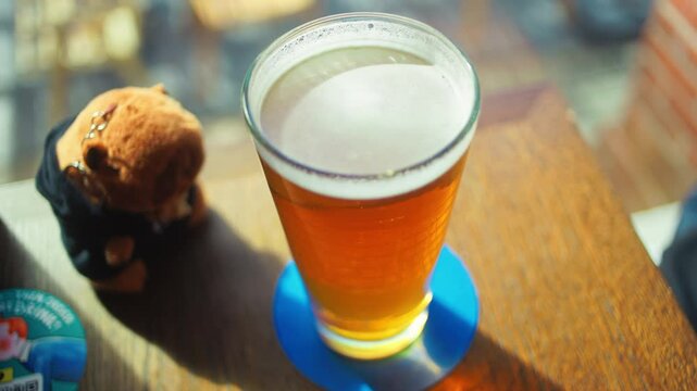 Enjoying a Refreshing Beer Delightfully Positioned on a Table Alongside a Cute and Charming Toy Companion