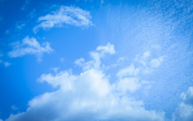 Bright blue sky with fluffy white clouds and soft sunlight shining