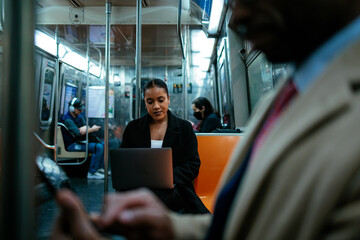 Businesswoman working on laptop while riding on subway