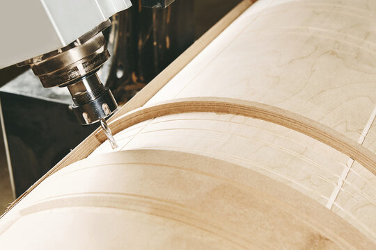 a four-axis numerically controlled woodworking machine cuts out complex lines on the canvas. CNC, computer control.