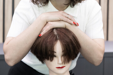 Mannequin head with artificial hair used by beauty student to learn precision haircutting and...
