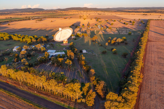 Aerial view of a large satellite dish on rural farmland in late afternoon sunshine