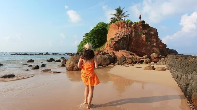 Excited Tourist smiley Woman Running Joyfully in Scenic Sri Lanka sunny beach.Parrot island popular landmark attraction. Mirissa coastline. Sri lanka travel sightseeing concept.