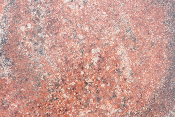Close-up view of a rugged reddish granite stone surface showcasing unique natural patterns and textures. This stone features a diverse array of mineral inclusions, creating visual interest.