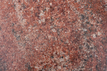 Close-up view of a rugged reddish granite stone surface showcasing unique natural patterns and textures. This stone features a diverse array of mineral inclusions, creating visual interest.