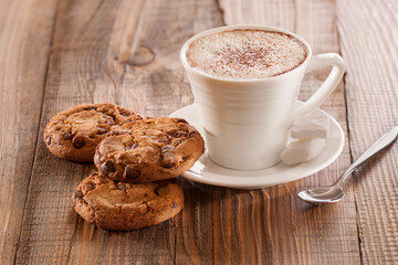 Oatmeal chocolate chip cookies with cappuccino on wooden background with spoon and sugar. 