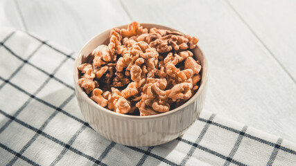 Shelled walnuts resting in a bowl on a checkered tablecloth create an inviting scene, highlighting a nutritious and delicious snack perfect for any healthy lifestyle