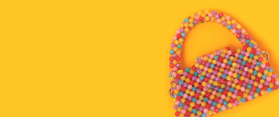 Banner with handcrafted cute bag made from multicolored beads on a yellow background.