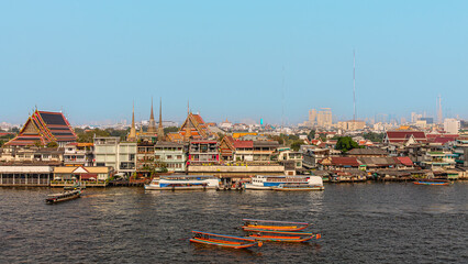 Cityscape view of riverside temples and boats during daytime in Bangkok, Thailand