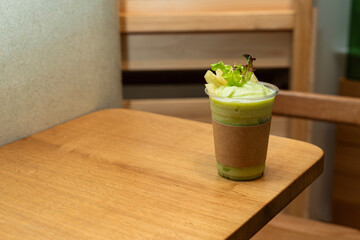 Green Smoothie in Takeaway Cup on Wooden Table in Cozy Cafe