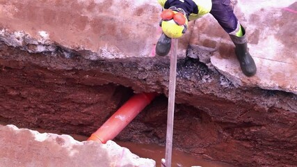 construction worker repairing sewage system drain pipes on a city street, HD video footage