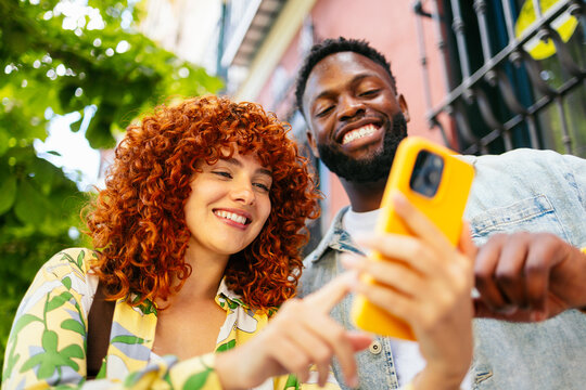 Two happy tourists are using a smartphone and smiling outdoors