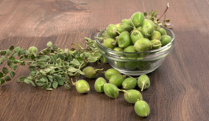 Fresh Green chickpeas on a branch, and in the pod, isolated on wooden background.