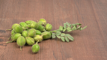 Fresh Green chickpeas on a branch, and in the pod, isolated on wooden background.