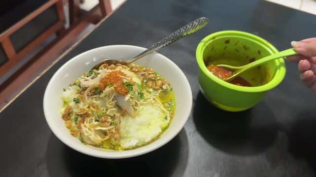 Pouring sambal to bubur ayam (chicken porridge) because Indonesian people love spicy. Cisauk, BSD - April 21, 2025