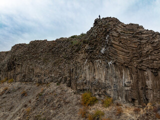 Person on Basalt Columns Under Cloudy Sky. Alumine, Neuquen, Argentina