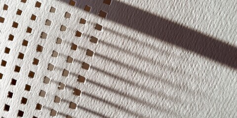 Obraz premium Close-up of perforated white paper with grid pattern and punched holes 