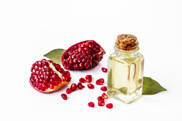 Pomegranate seed oil in a glass bottle and fresh fruit on a table, close up