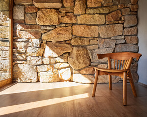 Wooden chair and stone wall in a sunny room