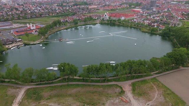 Orbit Aerial of Massive Lake with Trees and Knokke Skyline | FlyLens 4K