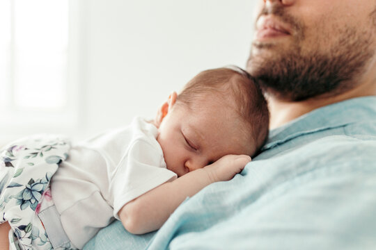 Newborn baby girl sleeping on father's chest.