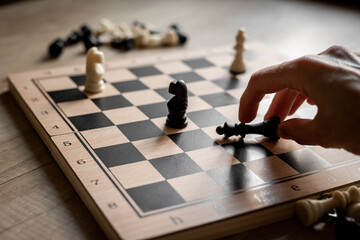 Hand is moving chess piece on chessboard. Game concept