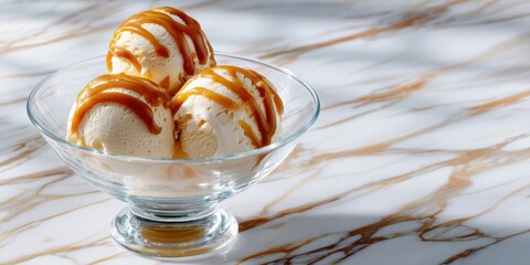Glass bowl with three scoops and caramel drizzle, white marble background