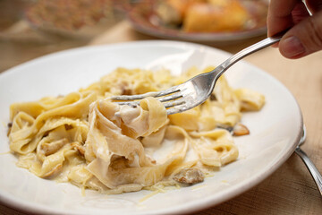 Creamy fettuccine pasta dish served on a white plate with fork lifting noodles for a delicious meal